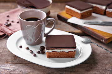 Delicious chocolate brownies on plate and coffee mug, on wooden background