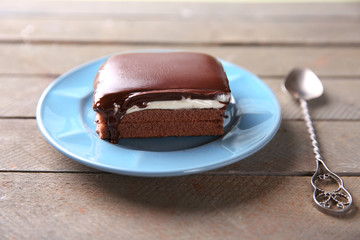 Delicious chocolate brownies on plate, on wooden background
