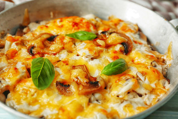 Roasted mushrooms, chicken and cheese gratin in pan, on wooden background