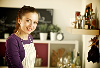Young woman standing in her kitchen near desk