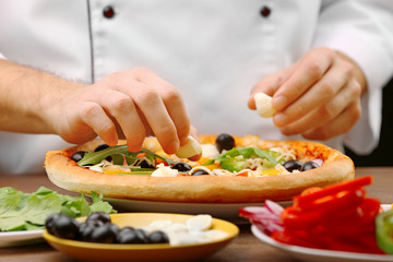 Cook making delicious pizza at the restaurant, close-up