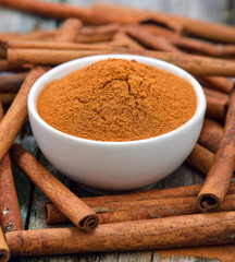 Cinnamon sticks and powder cinnamon in the bowl on table