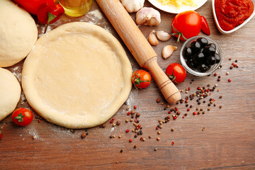 Dough basis and ingredients for pizza, on the table
