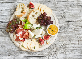 delicious appetizer to wine - ham, cheese, grapes, crackers, figs, nuts, jam, served on a light...