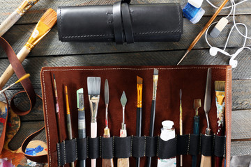 Leather case with items for drawing, on wooden background