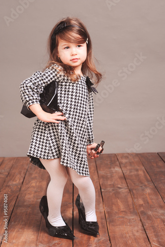 "Baby girl 4-5 year old posing in room. Standing on wooden floor over