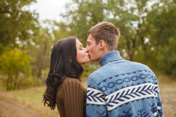 A loving couple kissing in autumn park outdoors