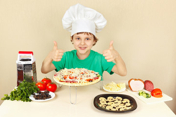 Little boy in chefs hat enjoys a cooking pizza