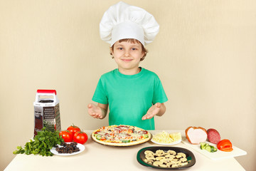 Young smiling chef in chefs hat enjoys a cooking tasty pizza