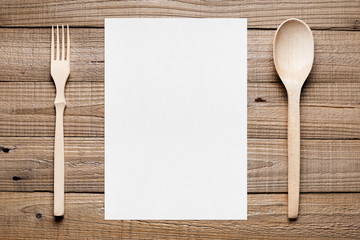 Paper for menu and wooden fork and spoon on table top view