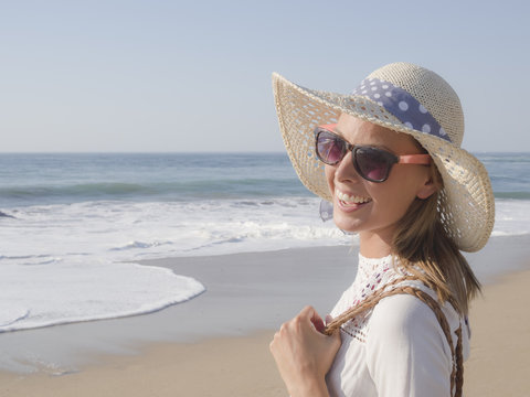 happy fashion blonde girl smiling portrait in the beach, wearing hat and sunglasses, profile photo