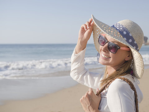 happy fashion blonde girl smiling portrait in the beach, wearing hat and sunglasses, profile photo