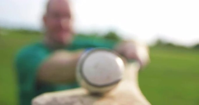 Balancing Sliotar Close Up. a player who is out of focus balances a sliotar on a hurley towards the camera. close up. Ball is in focus
