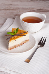 Vanilla cheesecake on a white plate and cup of tea