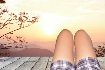 The legs of a woman lying on a wooden floor after sunset .