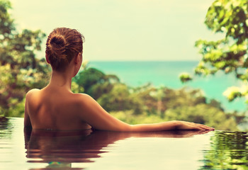 Beautiful girl rests in the swimming pool, sunbathing. Spa treatments. 
