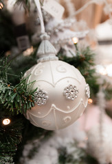 Bauble in christmas tree. Silver color. Silver color.
Warm lights blurry in background.