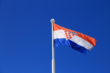 Flag of Croatia with flag pole waving in the wind with blue sky in background
