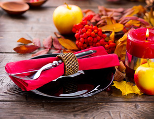 Thanksgiving wooden table served, decorated with bright autumn rowan leaves