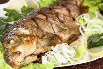 Roasted carp fish with vegetables entirely. Traditional Christmas menu.