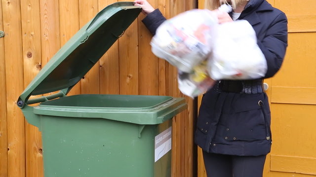Woman throwing garbage into litter-box in outside and leaving.