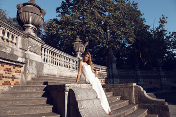 beautiful blond woman wears wedding dress,posing beside antic villa