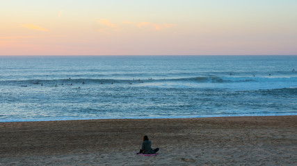 Fototapeta na wymiar Surfer girl waiting for her boyfriend on the beach at sunset