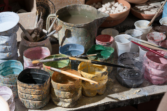 Work table of a pottery decorator of Caltagirone with different color containers and paintbrushes