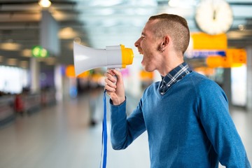Redhead man shouting by megaphone over white background