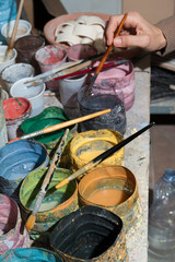 Work table of a pottery decorator of Caltagirone with different color containers and paintbrushes