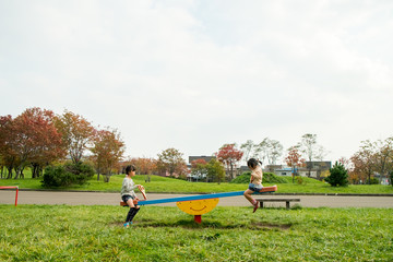 Obraz na płótnie Canvas 公園のシーソーで遊ぶ子供達