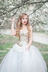Fototapeta na wymiar Young beautiful blonde woman in blooming garden. Bride