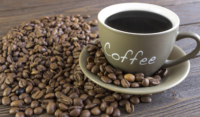 Cup of coffee  with beans standing on a wooden table.  blurred, focus on mug