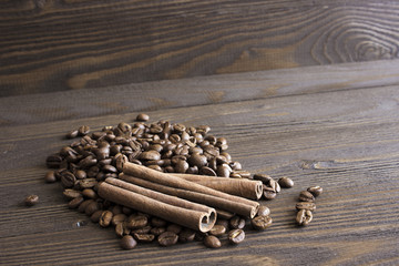 Coffee beans and cinnamon sticks bark lie on a wooden table. Blur, focus on near-stick