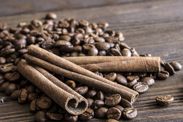 Coffee beans and cinnamon sticks bark lie on a wooden table. Blur, focus on near-stick