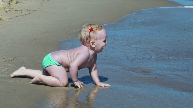 little child exploring the sand and sea waves slow motion