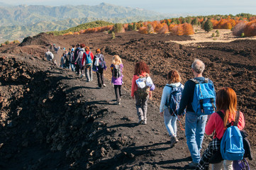Group of hikers walking on a trail on to the north side of Mount Etna - obrazy, fototapety, plakaty