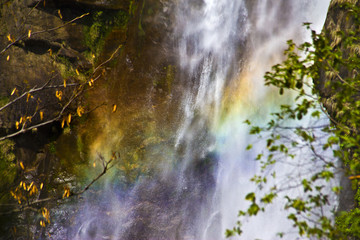 Waterfall in mountains and rainbow in front of it