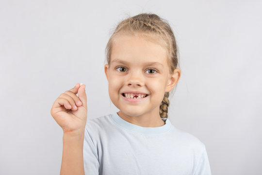 The girl proudly showing her fallen baby tooth