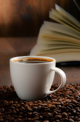Composition with white cup of coffee and open book