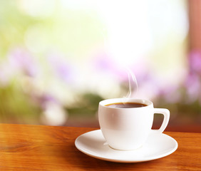 Cup of coffee on table on bright background