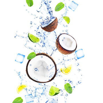 Coconuts, slices of lemons and limes with mint leaves in water splashing isolated on white