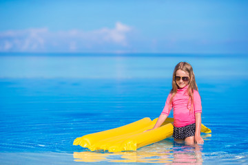 Adorable girl with inflatable air mattress in outdoor swimming pool