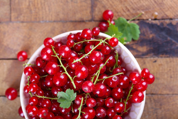Fresh red currants in bowl on wooden table close up