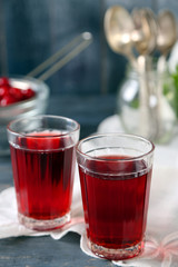 Sweet homemade cherry juice on table, on color background