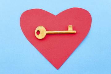 Red heart and a golden key on a blue background
