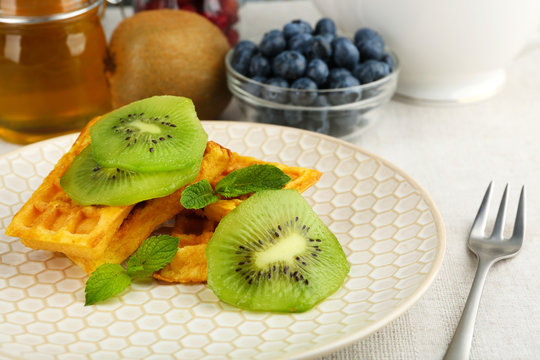 Sweet homemade waffles and fresh kiwi fruit on plate, close-up