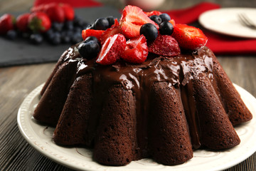 Delicious chocolate cake with berries in plate on table, closeup