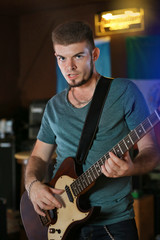 Young man playing on electric guitar at pub