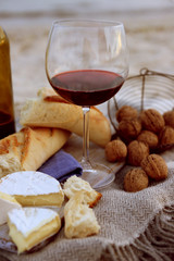 Beautiful romantic composition of red wine, bread and nuts on sandy beach